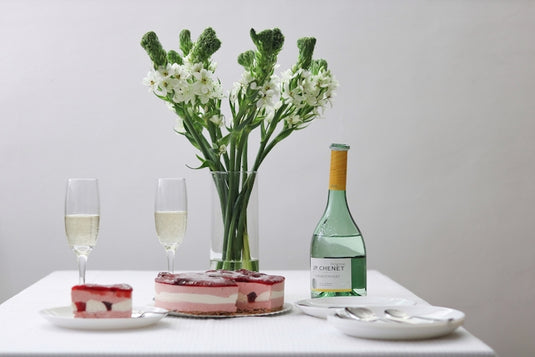 A table topped with a vase of flowers next to a bottle of wine