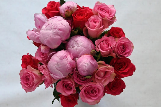 Vibrant bouquet of pink peonies and red roses.