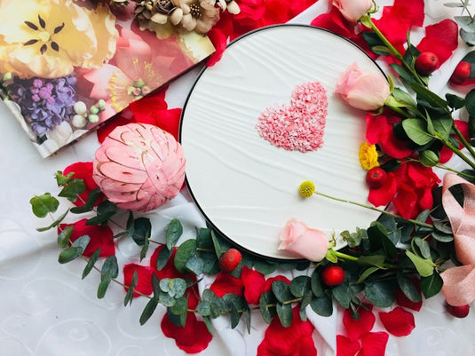 a white plate topped with a pink frosted heart surrounded by flowers