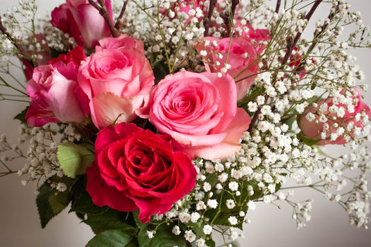 a vase filled with pink roses and baby's breath