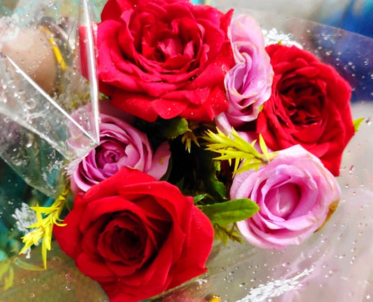 a bouquet of red and pink roses sitting on top of a table