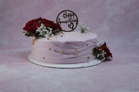 Anniversary cake with roses and 'happy anniversary' topper.