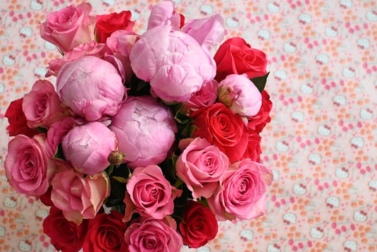 Vibrant bouquet of pink peonies and red roses.